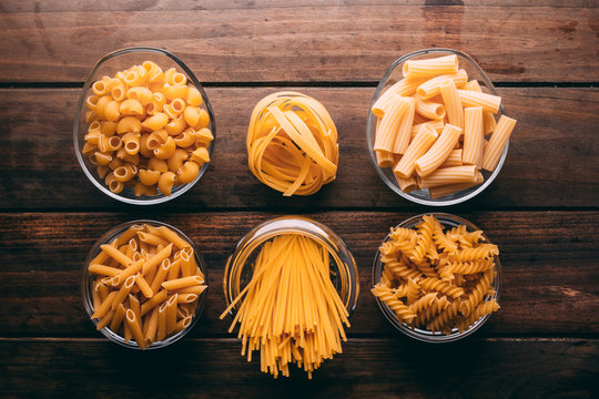 Top view of a rustic wooden table full of different types of pasta, Carbohydrates