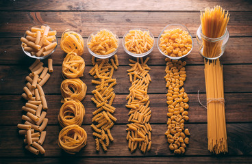 Top view of a rustic wooden table full of different types of pasta, Carbohydrates