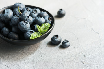 Blueberries, summer season, berries in black bowl. Selective focus, toned image, closeup.