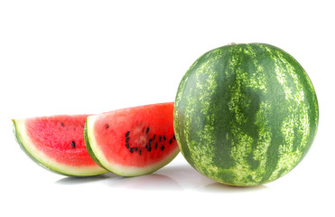 A large ripe watermelon next to watermelon slices on a white isolated background