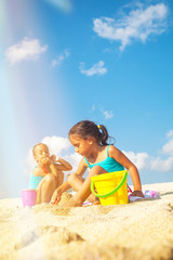 Children on the beach. Beautiful little girls are playing on the sand by the sea.