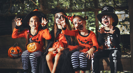 happy Halloween! a group of children in suits and with pumpkins in forest.
