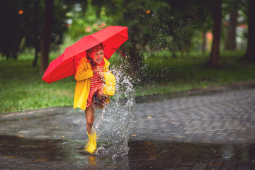 hap happy child girl with an umbrella and rubber boots in puddle  on autumn walk
