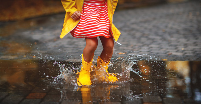 leg of child in rubber boots in puddle  on autumn walk