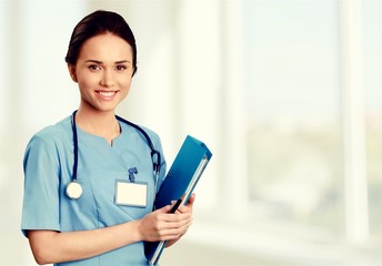 Attractive young female doctor with blurred hospital interior on