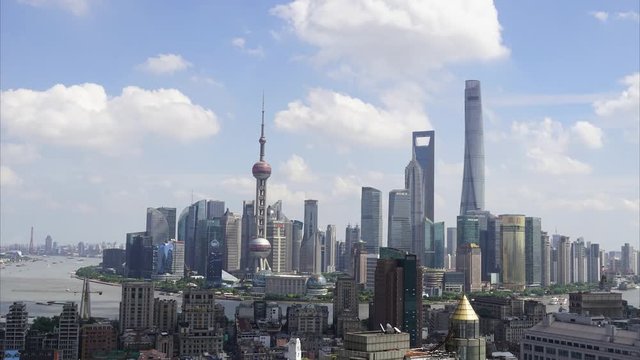 Wide shot Shanghai Lujiazui business district timelapse. Chinese city downtown time-lapse with beautiful clear day with white fluffy clouds. Cityscape of Pudong in urban China in daytime.