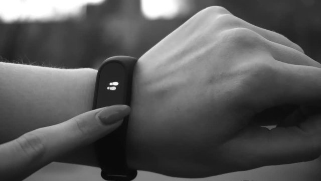 Young woman using wearable fitness tracker, monochrome. Entertainment and technology concept. Close-up shot of woman hand with smart watches