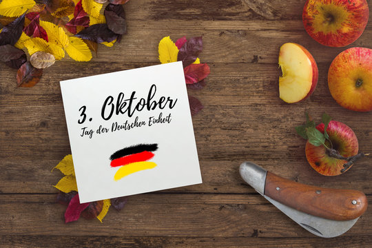 Herbstlaub, Äpfel und Karton mit Aufschrift "3. Oktober - Tag der Deutschen Einheit" 
