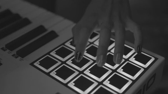 Drum machine in the night club playing live set. Stock. Fingers tapping drum pads on a digital beatmaker close-up, monochrome. Dj starts playing music set in the club playing the drum machine