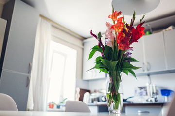 Modern kitchen design. Interior of white and silver kitchen decorated with flowers. Cozy apartment