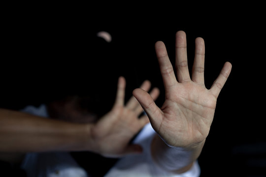The palm of a female hand giving the signal to stop. The dark, moody image is a concept of a woman being abused, raped, beaten, threatened, robbed, domestic violence etc.