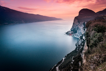 The cliffs of Tremosine sul Garda, sunset behind the plateau and Lake Garda, Italy