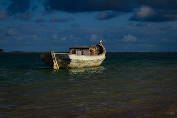 Small old and worn boat anchored on the coast