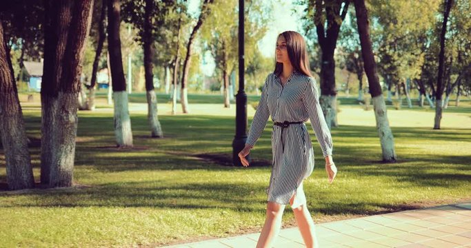 Young beautiful girl walks in the park at a rapid pace
