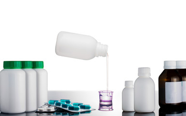 Pouring medicine syrup, and medicine bottles, on top of a reflective surface, white background