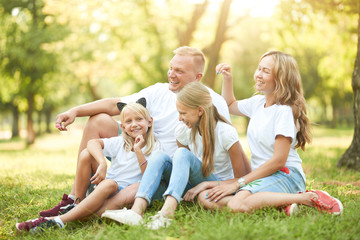 Cheerful family sitting on the grass during a picnic in the park