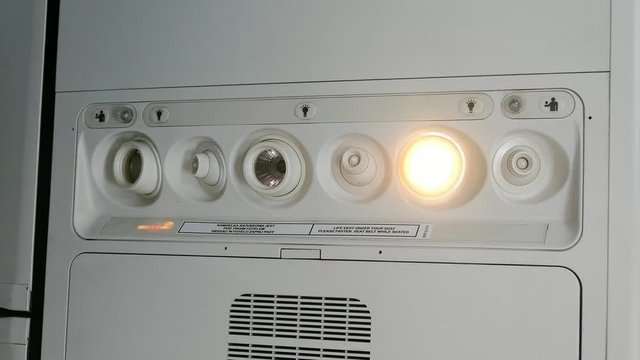 Passenger Switches Reading Lamp in Airplane Overhead Panel