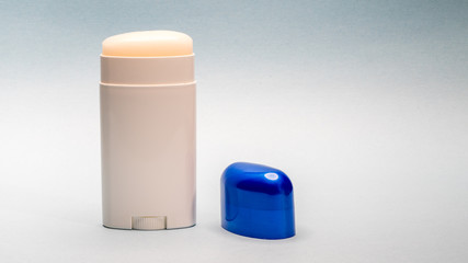 Deodorant stick roll on, with blue cap next to it.