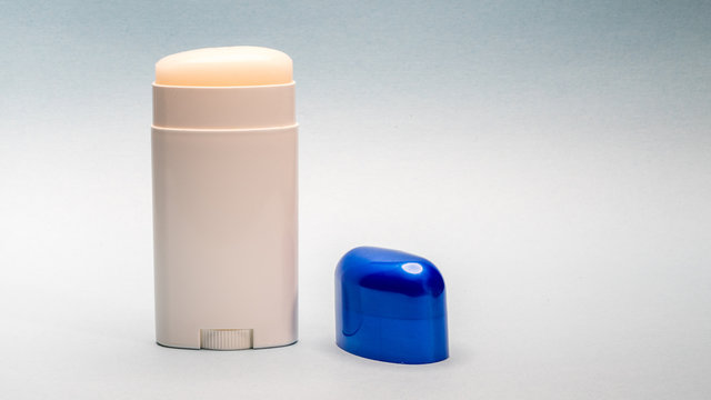 Deodorant stick roll on, with blue cap next to it.