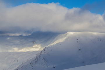Winter alpine scenery with fresh snow, mist, and beautiful evening light