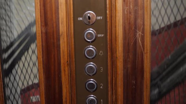 View of wooden number panel as floors rush by inside an antique elevator