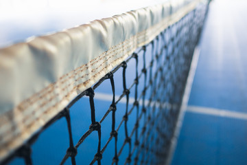 net of tennis with white stripe in blurred blue court