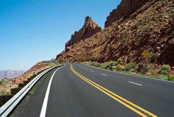 Lonely, Winding Asphalt Road in Arizona, USA with Two Yellow Center Lines and Rocky Orange Hillside