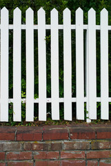 Wooden Picket Fence Painted White on a Base of Red Bricks