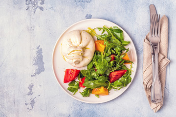 Italian cheese Burrata with fresh arugula, tomatoes, olive oil