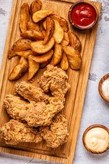 Fried chicken wings with fried potato slices.