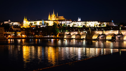 Prague by night. Prague Castle and Charles Bridge reflected in Vltava River. View from Smetana Embankment. Praha, Czech Republic.