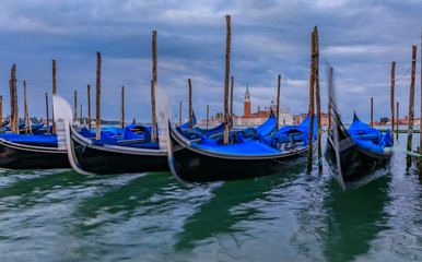 Gondolas along Grand Canal at St Marco square with San Giorgio Maggiore church at sunrise in Venice Italy