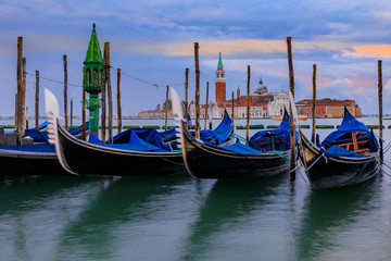 Gondolas along Grand Canal at St Marco square with San Giorgio Maggiore church at sunrise in Venice Italy