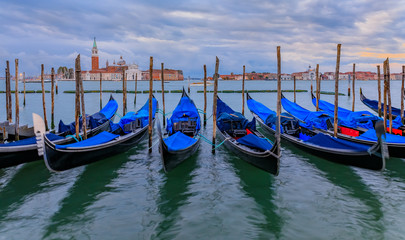 Gondolas along Grand Canal at St Marco square with San Giorgio Maggiore church at sunrise in Venice Italy