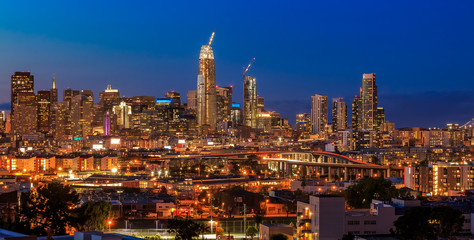 Naklejka premium San Francisco skyline panorama with city lights, the Bay Bridge and trail lights