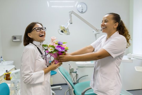 Two female dentists with a bouquet of flowers in the dental office. National Doctor's day.