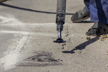 Workers repair the road, pour small cracks with bitumen to prevent further destruction of the road surface