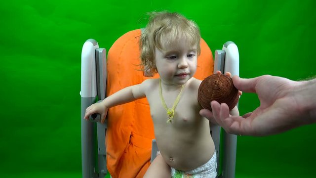 little child takes the ball from the hands of a man on a green background.