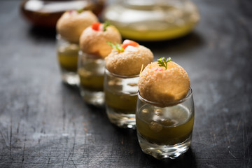Pani Puri is an indian road side chat item - 4 stuffed puris kept over small glasses filled with mint water © Arundhati