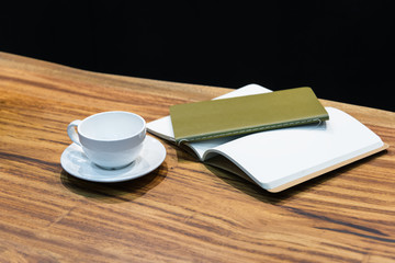 A cup of coffee with notebook on wooden table