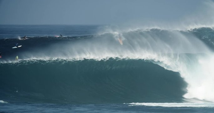 Big wave surfer on a large blue wave in Hawaii during dangerous storm conditions