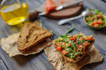 Red fish, arugula and sesame sandwich on a dark wooden background