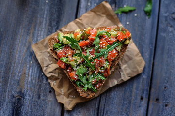 Red fish, arugula and sesame sandwich on a dark wooden background