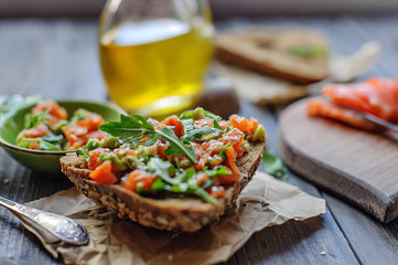 Red fish, arugula and sesame sandwich on a dark wooden background