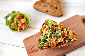Red fish, arugula and sesame sandwich on a light wooden background