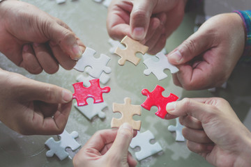 Hands of diverse people assembling jigsaw puzzle,  help support in teamwork to find common solution concept, top close up view