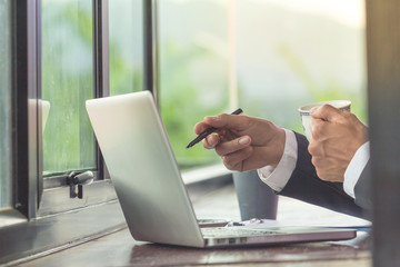 Business man working on laptop computer and drinking coffee.
