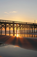 Early morning at the atlantic ocean beach. Beautiful marine landscape with sun rising over calm atlantic ocean beach with wooden pier. South Carolina, Myrtle Beach area, USA. Vacation background.
