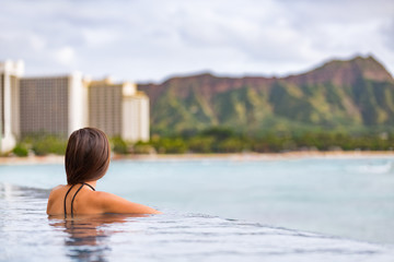 Hawaii vacation Honolulu travel tourist woman relaxing in swimming infinity pool at luxury resort hotel in Waikiki beach, watching sunset. Girl on USA summer travel landscape banner panoramic.