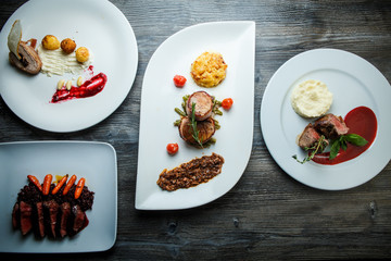 wooden table topped with white plates with different types of food in restaurant